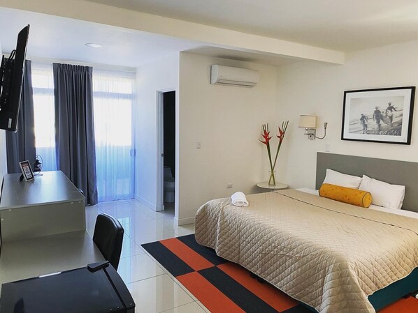 Una habitación de hotel con cama, escritorio, silla, televisión y un cuadro en la pared.