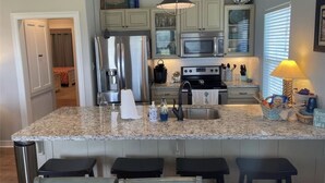 Una cocina con encimeras de granito, electrodomésticos de acero inoxidable y un cartel que dice 'Beach House'.