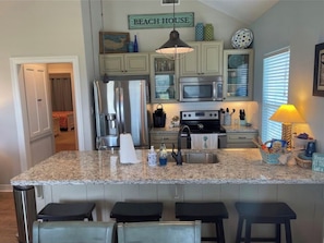 A kitchen with granite countertops, stainless steel appliances, and a 'Beach House' sign.
