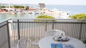 En balkon med et bord dækket til to, der kigger ud over en havn med både og bygninger.