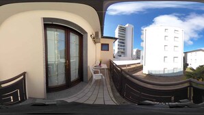 Un edificio moderno con una entrada curva, un pequeño espacio de asientos al aire libre y vistas de edificios altos circundantes.