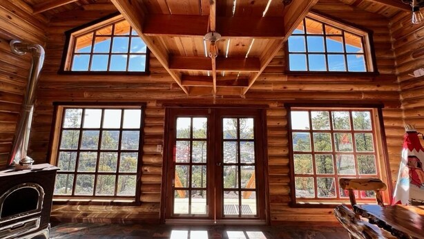 A log cabin interior with wooden walls, a central door, and large windows. - Quinn cabañas (Bocoyna)