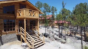A wooden cabin with a porch and a stone foundation. - Quinn cabañas (Bocoyna)