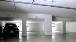 Un estacionamiento vacío con columnas numeradas y un coche estacionado en una de las plazas.