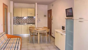 Cocina compacta con comedor, televisor y sofá.
