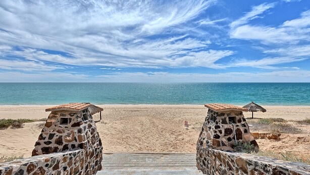 A beach with a stone pathway leading to a thatched-roof structure. - Paradise Villa 19 by Kivoya (Puerto Peñasco)