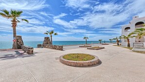 A coastal promenade with stone walls, palm trees, and a view of the sea. - Paradise Villa 19 by Kivoya (Puerto Peñasco)