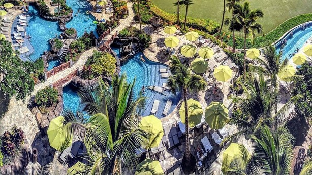 Un complexe hôtelier doté de plusieurs piscines, de palmiers et offrant une vue sur l’océan.