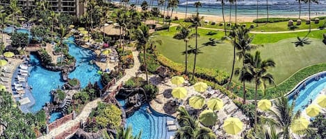 Un complexe hôtelier doté de plusieurs piscines, de palmiers et offrant une vue sur l’océan.