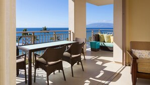 Un balcon avec une table et des chaises, un canapé et une vue sur l’océan et les montagnes.