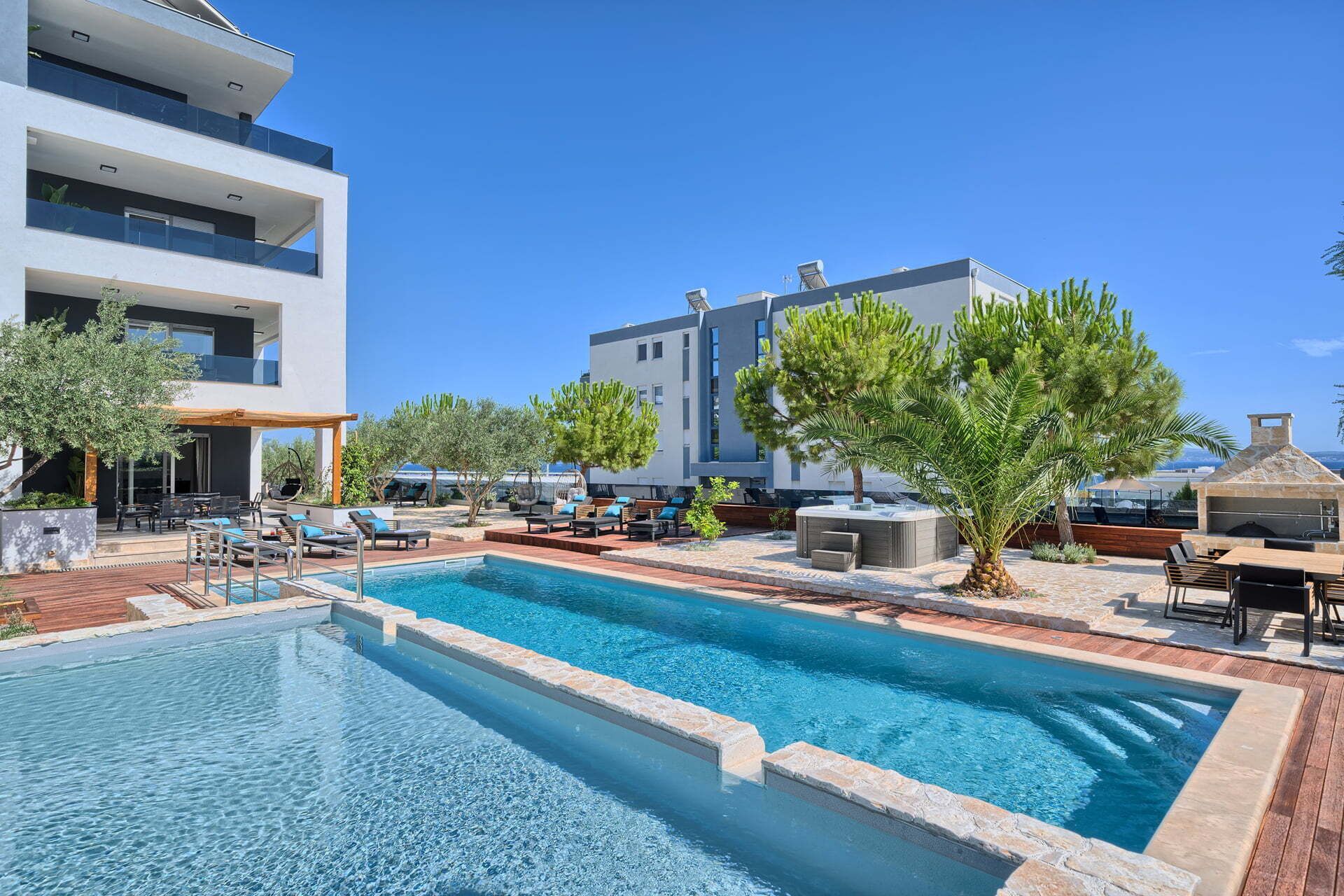 A modern hotel with a rooftop pool, outdoor seating, and a view of the sea.