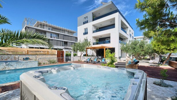 Ein modernes Hotel mit Pool auf dem Dach, Sitzgelegenheiten im Freien und Blick aufs Meer.