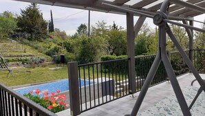 Un espacio al aire libre cubierto con piscina, baranda de metal y jardín con diversas plantas y flores.