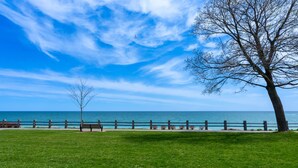 A grassy park area with a wooden fence, benches, and a tree. - Lakeside Modern House 4BR - Steps to the lake (Bowmanville)