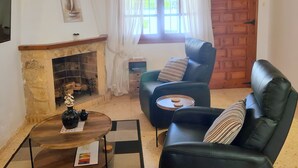 Una sala de estar acogedora con chimenea, sillones de cuero, una mesa de centro y una puerta de madera.