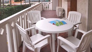 A round white table with four white chairs on a balcony with a white railing. - Holiday apartment with balcony and air conditioning (Lignano Sabbiadoro)