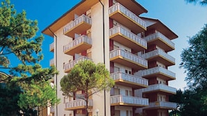 A multi-story building with balconies, likely a hotel or apartment complex. - Holiday apartment with balcony and air conditioning (Lignano Sabbiadoro)