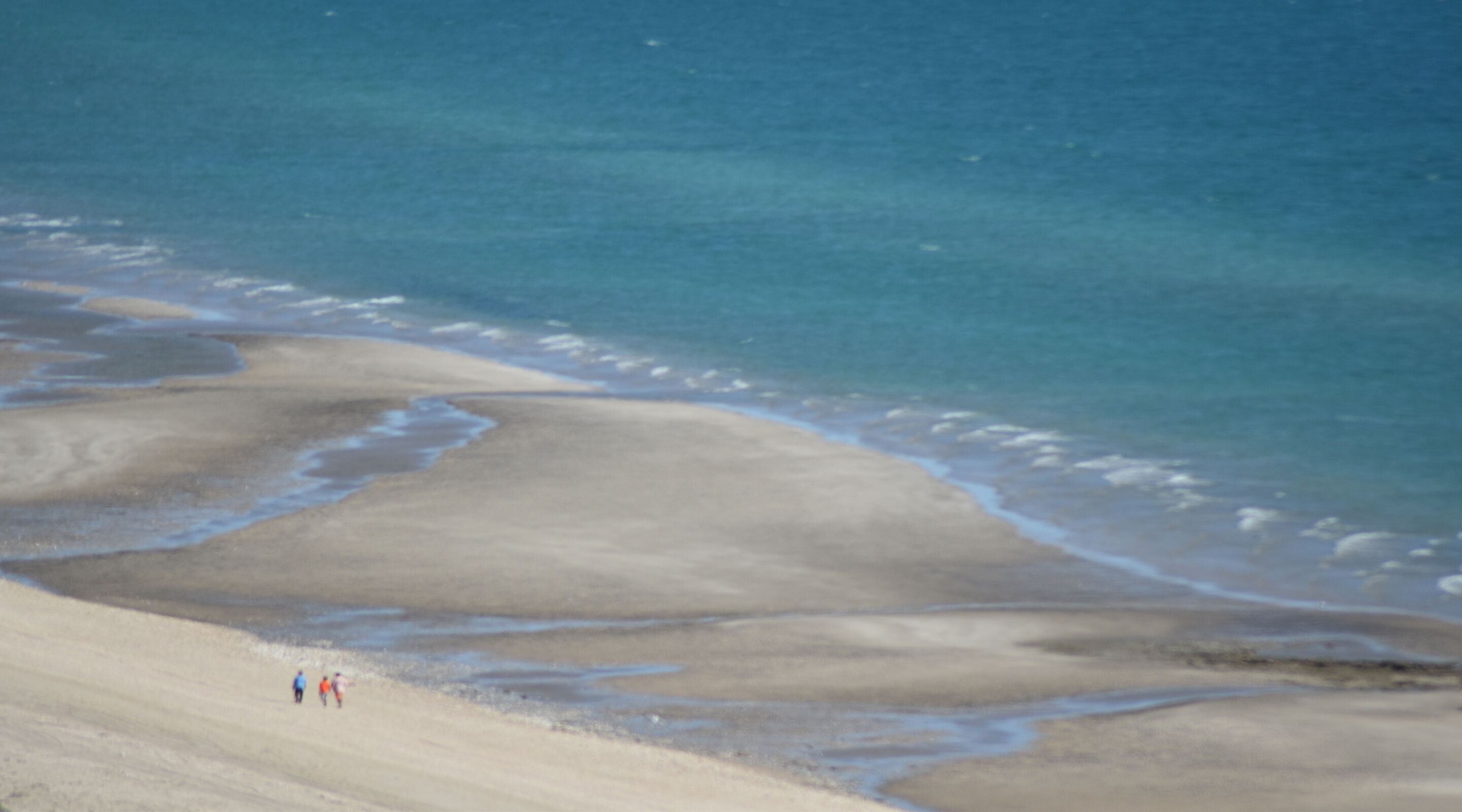 A beach with a wide sandy area and a calm sea.