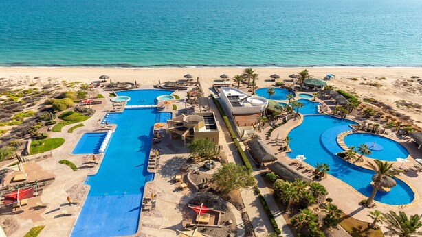 A resort with multiple swimming pools, a beach, and palm trees.