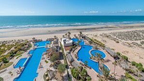 A resort with multiple swimming pools, beachfront views, and a sandy beach.