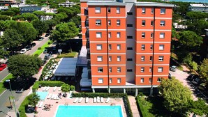 Un hotel a più piani con piscina, area salotto esterna e ristorante.