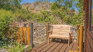 A wooden bench on a wooden deck with a stone wall and a metal gate in the background. - Brook Cottage - village cottage close to pubs and walks (Coniston)