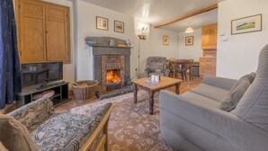 Una sala de estar acogedora con chimenea, un sofá, un televisor y un comedor.