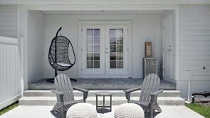 Une terrasse avec deux fauteuils Adirondack, une petite table et deux poufs ronds.