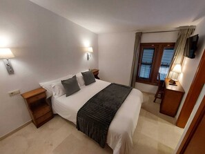 Relax in a spacious room with a large bed, wooden nightstand, and flat-screen TV.