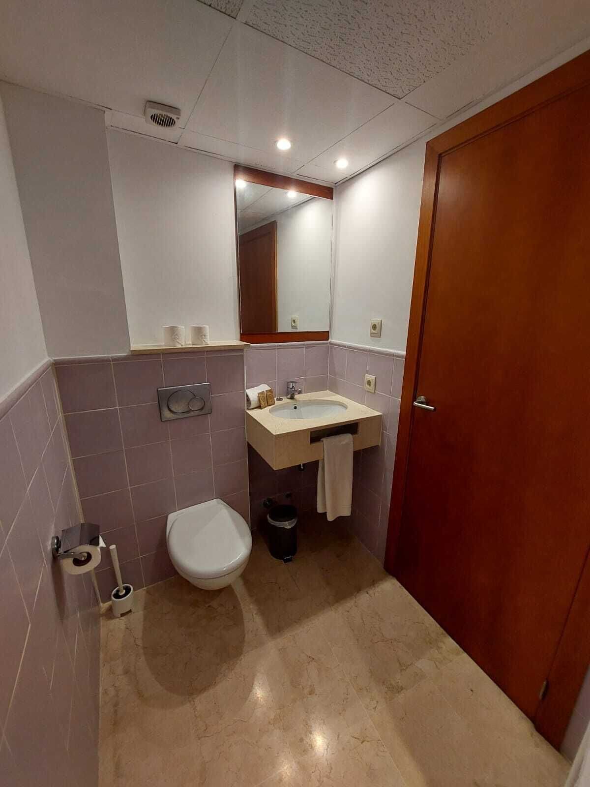 Un baño pequeño con inodoro, lavamanos y espejo.