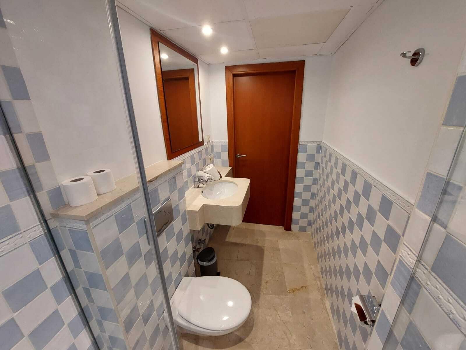 A small bathroom with a toilet, sink, and mirror.