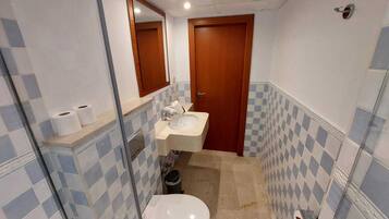 A small bathroom with a toilet, sink, and mirror.