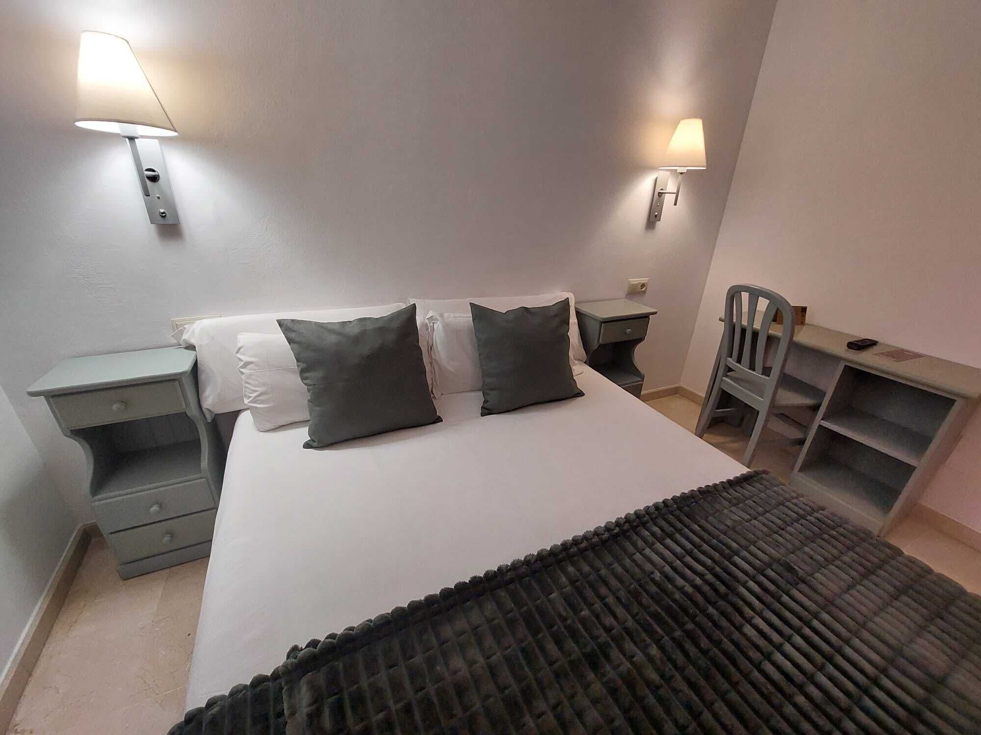 Ein Schlafzimmer mit einem Bett, zwei Nachttischen, einem Sessel und zwei Wandleuchten.