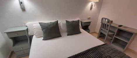 Ein Schlafzimmer mit einem Bett, zwei Nachttischen, einem Sessel und zwei Wandleuchten.