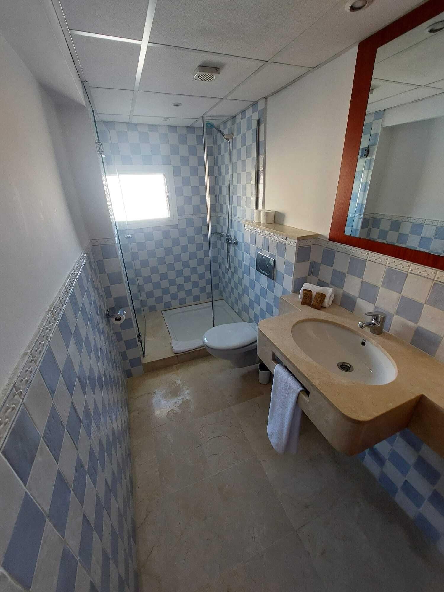 A bathroom with a checkered tile pattern, a sink, a toilet, and a shower.