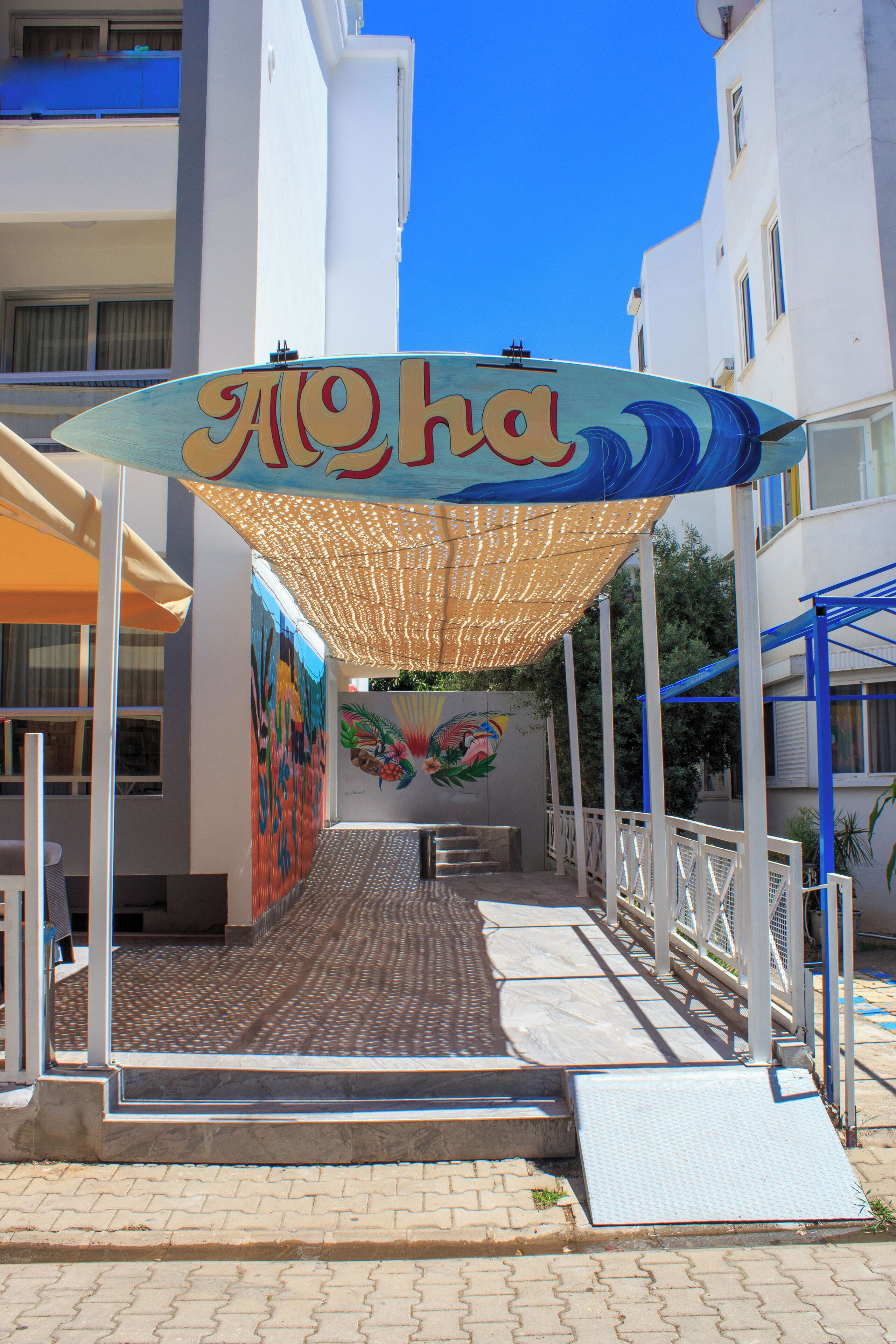 A hotel entrance with a colorful awning and a mural.