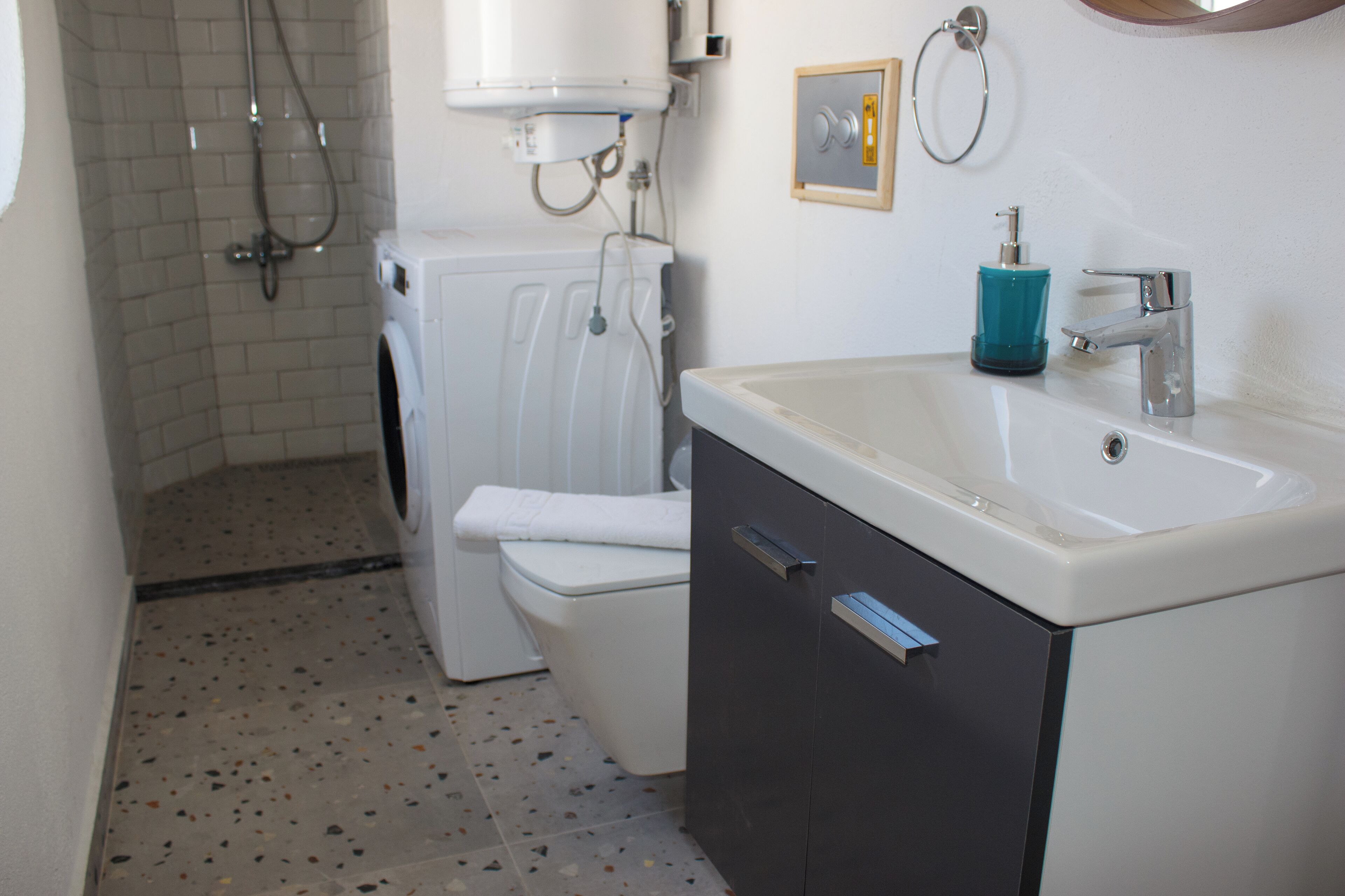Een badkamer met een wasmachine, toilet, wastafel en douche.