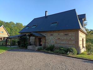 A stone building with a sloped roof and a covered porch. - Janville Estate (Paluel)