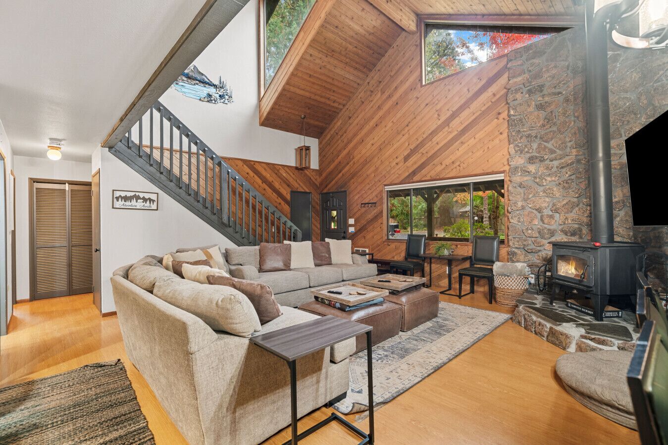A spacious living room with a large sofa, a fireplace, and a stone wall.