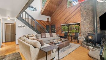 A spacious living room with a large sofa, a fireplace, and a stone wall.