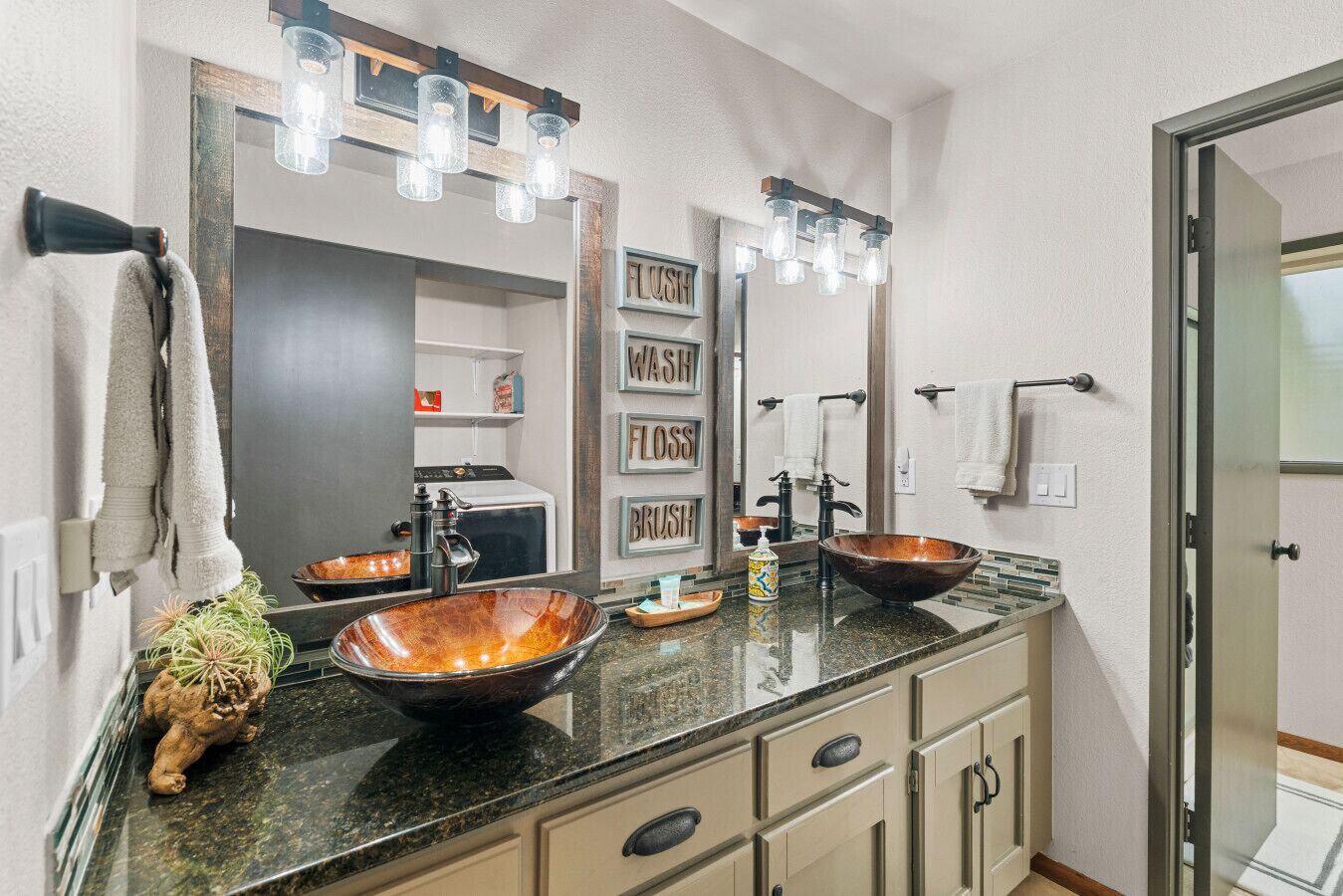 A modern bathroom with two vessel sinks, a large mirror, and a towel rack.
