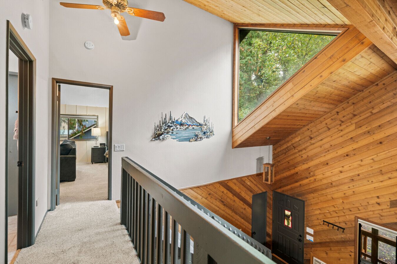 A modern interior with a wooden ceiling, a staircase, and a large window.