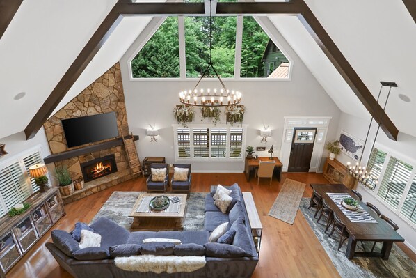 A spacious loft with a stone fireplace, a large sofa, and a dining area.
