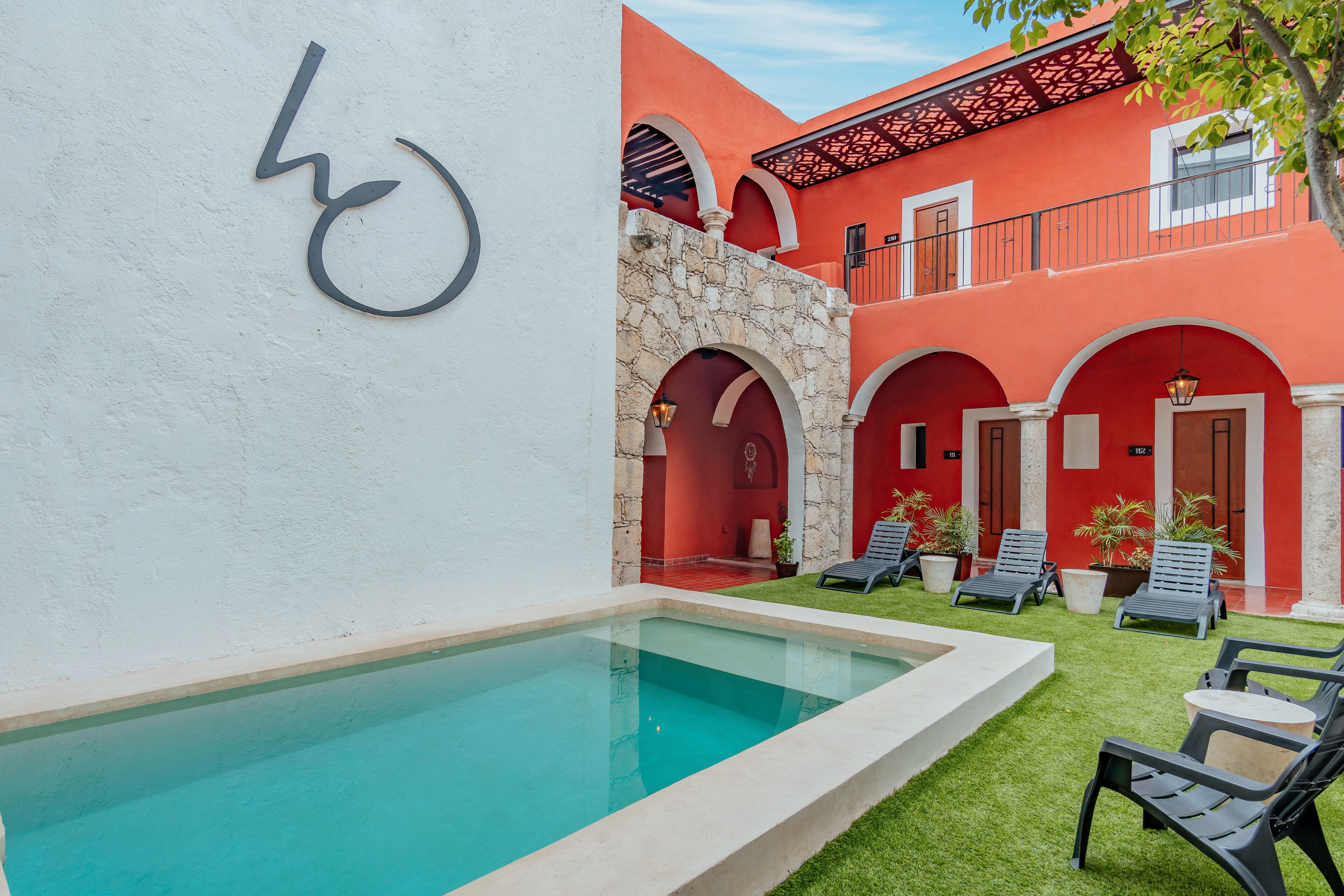 Un área de piscina con sillas de descanso y un muro de piedra.