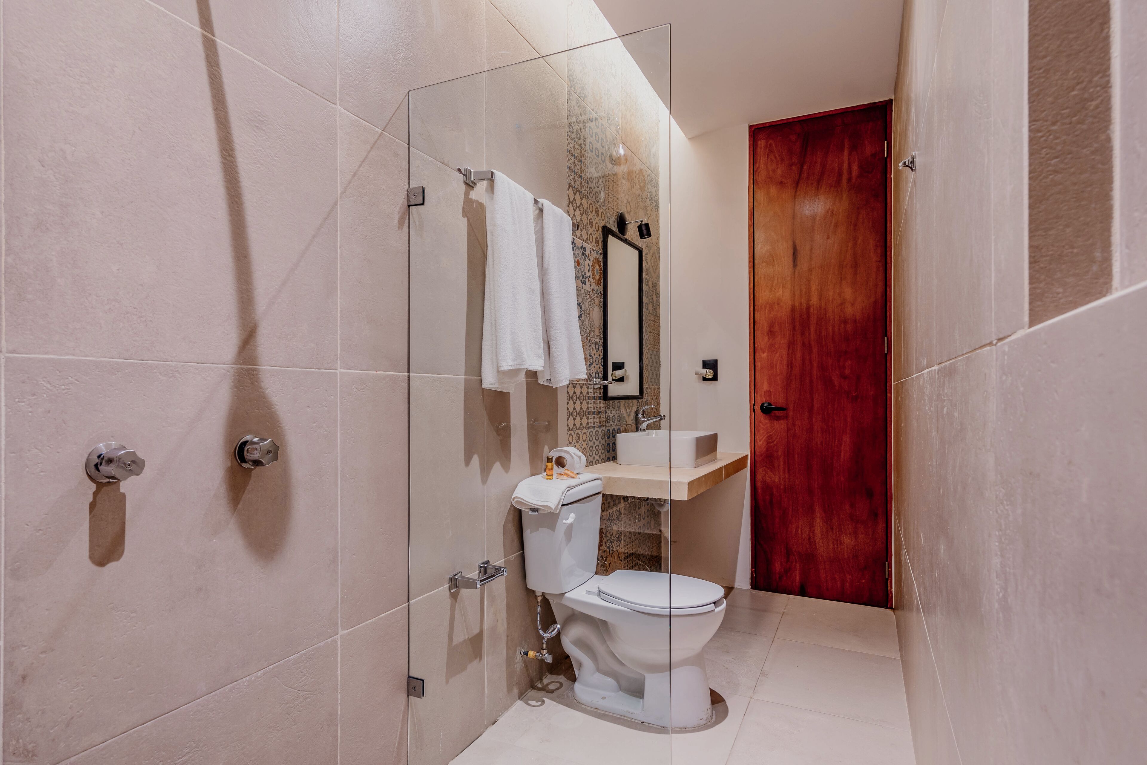 Un baño moderno con cabina de ducha de vidrio, inodoro y puerta de madera.