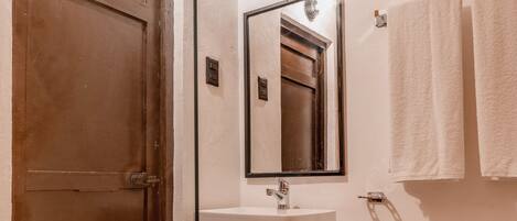 A bathroom with a wooden door, a white sink, a mirror, and a toilet.