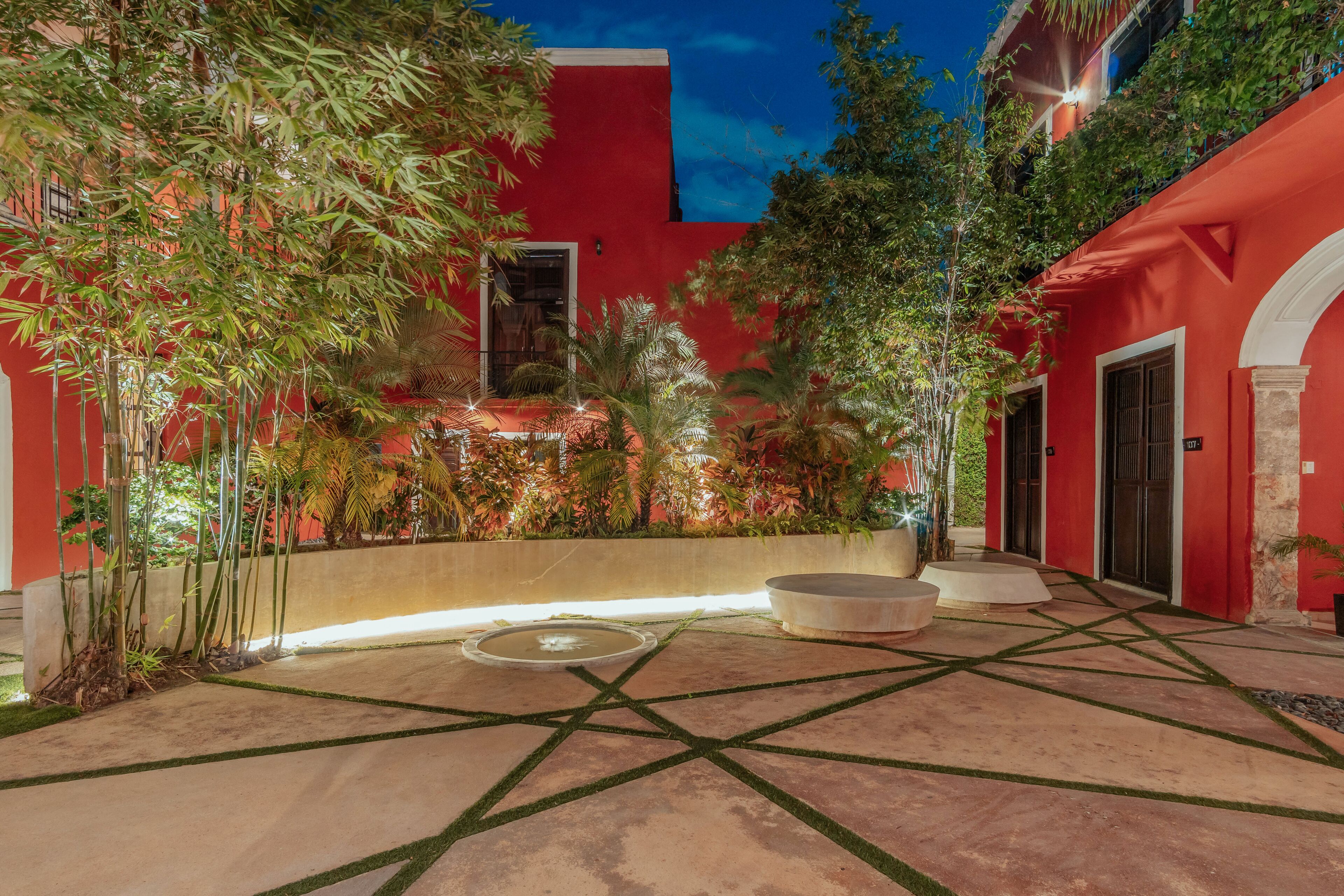 A courtyard with a red building, a water feature, and a seating area.