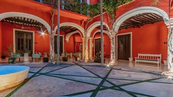 Un patio con piscina, mobiliario exterior y fachada de edificio roja.