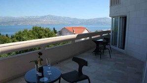 Ein Balkon mit Tisch und Stühlen mit Blick auf ein Gewässer und entfernte Berge.