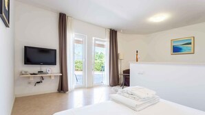 Une chambre d’hôtel avec un lit, un téléviseur fixé au mur, un bureau avec une lampe et une vue sur l’extérieur par la porte.